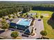 Aerial view of community pool, clubhouse, tennis courts, and green space surrounded by dense forest at 56 Mist Wood Ct, Pittsboro, NC 27312
