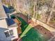 Aerial view of backyard with manicured lawn, wooden deck, fence, and mature trees casting shadows at 5624 Bennettwood Ct, Raleigh, NC 27612