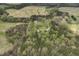 Aerial view showcases home and wooded acres surrounded by fields and roadways at 610 Flemingtown Rd, Henderson, NC 27537