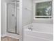 Bright bathroom featuring a glass shower stall and a large soaking tub beneath a window at 709 Conifer Ct, Creedmoor, NC 27522