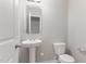 Charming half-bath features a pedestal sink, toilet, and stylish mirror at 709 Conifer Ct, Creedmoor, NC 27522