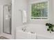 Relaxing bathroom with a soaking tub, shower, and a large window for natural light at 709 Conifer Ct, Creedmoor, NC 27522