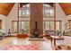 Bright living room with a brick fireplace, wood floors, and soaring windows showcasing the wooded surroundings at 735 Jordan Hills Loop, Chapel Hill, NC 27517