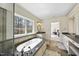 Bright bathroom featuring a large tub, dual vanities, stone countertops, and tiled flooring at 7504 Everton Way, Wake Forest, NC 27587