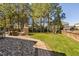 Beautifully landscaped backyard featuring a stone fireplace and manicured lawn at 804 Cambridge Hall Loop, Apex, NC 27539