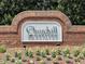 Beautiful brick entrance sign to Churchill Estates with manicured landscaping, flowers, and mature greenery in the background at 804 Cambridge Hall Loop, Apex, NC 27539