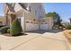 Three-car garage with white doors and a large driveway with professional landscaping at 804 Cambridge Hall Loop, Apex, NC 27539