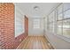 Cozy sunroom with a brick accent wall, built-in shelving, wood-look floors, and ample natural light at 818 Eastern Ave, Rocky Mount, NC 27801