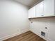 Bright laundry area featuring white cabinets, wooden floor, and convenient hookups for washer and dryer at 136 Tee Time Ter, Benson, NC 27504