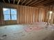 Unfinished living room featuring stud walls, subfloor, and a window overlooking a neighboring home at 163 Noramac Ct, Selma, NC 27576