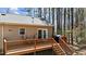 View of the back deck featuring a grill, chairs and stairs leading down into the wooded backyard at 170 Buckaroo Dr, Louisburg, NC 27549