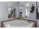 Corner bathtub with a tile surround, two mirrors and an accent wall with a decorative wreath at 170 Buckaroo Dr, Louisburg, NC 27549
