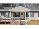 Inviting front porch with a porch swing, white railing, brick foundation, and a pink front door with welcome wreath at 170 Buckaroo Dr, Louisburg, NC 27549