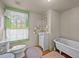Bathroom features vintage-style tub, wood floors, and a bright green window frame at 2409 Hodges Rd, Burlington, NC 27217