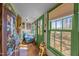 Bright sunroom with large windows, green trim, cozy seating, and charming decor at 2409 Hodges Rd, Burlington, NC 27217