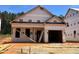 Exterior view of a new construction home with a visible garage and a door leaning against the side, set against a clear blue sky at 346 Bluejay St, Clayton, NC 27520