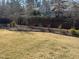 Manicured back yard with lush trees, landscaping, a well maintained lawn, and a black metal fence at 3847 Stoneridge Forest Dr, Raleigh, NC 27612