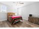 Cozy bedroom featuring hardwood floors, two windows, a ceiling fan, and a wicker-textured headboard at 3847 Stoneridge Forest Dr, Raleigh, NC 27612