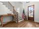 Elegant foyer with hardwood floors, staircase, console table, and front door with wreath, creating a welcoming entrance at 3847 Stoneridge Forest Dr, Raleigh, NC 27612