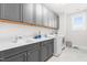 Bright laundry room featuring gray cabinets, white countertops, a stainless steel sink, and a modern washing machine at 3847 Stoneridge Forest Dr, Raleigh, NC 27612