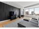 Bright living room with large windows, black accent wall, sleek TV console, and comfortable gray sectional at 400 W North St # 1204, Raleigh, NC 27603