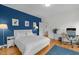 Bedroom featuring a blue accent wall, hardwood floors, and a well-lit workspace at 445 S Greensboro St, Carrboro, NC 27510