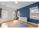 Bright bedroom featuring hardwood floors, natural light, and a bold blue accent wall at 445 S Greensboro St, Carrboro, NC 27510