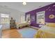 Charming bedroom with two twin beds, purple accent wall and cheerful decor at 445 S Greensboro St, Carrboro, NC 27510
