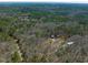 Aerial view shows the property surrounded by a mature forest and a lake in the distance at 471 Deer Run, Pittsboro, NC 27312