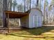 Exterior view of shed with overhanging roof and double doors, set on a grassy lot at 471 Deer Run, Pittsboro, NC 27312