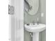 A clean powder room featuring a pedestal sink, round mirror, and fresh green walls at 6817 Osprey Landing Dr, Wendell, NC 27591