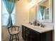 Bright bathroom featuring a double sink vanity, framed mirrors, and a window with blue curtains at 700 Treviso Ln, Apex, NC 27502