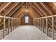 Unfinished attic space with exposed wood framing and a small window, perfect for storage or renovation at 78 Radcliffe Ct, Clayton, NC 27527
