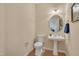 Charming powder room featuring pedestal sink, round mirror, and wood look flooring at 7920 Leonardo Dr, Durham, NC 27713