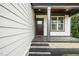 Inviting front porch with stone accents, decorative pillars, and a dark-stained wood door and adjacent window at 913 Clayton Rd, Angier, NC 27501