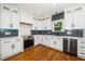 Well-lit kitchen with white cabinetry, stainless steel appliances, and a black backsplash; wood floors throughout at 913 Clayton Rd, Angier, NC 27501