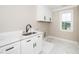 Well-lit laundry room with white cabinets, marble countertops, and a utility sink at 913 Clayton Rd, Angier, NC 27501