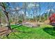 Spacious backyard showcasing mature trees, a well-manicured lawn, and a stone retaining wall at 100 Pebble Ridge Farms Ct, Cary, NC 27513