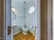 Charming powder room features hardwood floors, pedestal sink, and decorative round window at 101 Sundance Pl, Chapel Hill, NC 27514