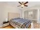 Primary bedroom with a large upholstered headboard, ceiling fan, and wood floors at 10411 Rosegate Ct # 202, Raleigh, NC 27617