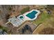 Aerial view of a community pool and clubhouse with parking, walking trails, playground, and mature trees at 105 Della St, Chapel Hill, NC 27516