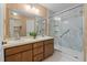 Bathroom featuring double sinks, wooden cabinets, large mirror, and shower with glass door at 1101 Esher Ct, Raleigh, NC 27609