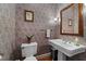 Charming powder room with pedestal sink, floral wallpaper, and decorative mirror at 1106 Aycock Ave, Burlington, NC 27215