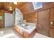 Rustic bathroom featuring knotty pine walls, soaking tub and skylight with relaxing decorations at 1106 Aycock Ave, Burlington, NC 27215