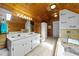 Rustic bathroom with knotty pine walls, double sinks, a large mirror, and a soaking tub at 1106 Aycock Ave, Burlington, NC 27215