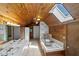 Rustic bathroom featuring knotty pine walls, a soaking tub, double sinks, and a skylight for natural lighting at 1106 Aycock Ave, Burlington, NC 27215