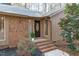 Inviting brick entryway with a classic wood door, enhanced by manicured landscaping and warm exterior lighting at 11808 Black Horse Run, Raleigh, NC 27613
