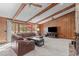 Open-concept living room with wood ceiling beams, stone fireplace, and access to back deck at 11808 Black Horse Run, Raleigh, NC 27613