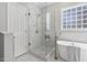 Bright bathroom featuring a glass shower, standalone tub, and block window for natural light at 1217 Wedgeland Dr, Raleigh, NC 27615