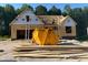 View of the new home construction with lumber on the ground and a dumpster in front of the home at 129 Tigris Ct, Zebulon, NC 27597